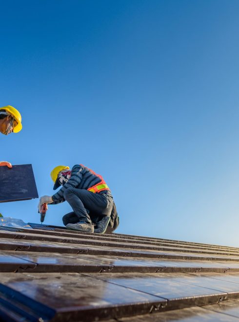 Two male workers wearing safety clothes Installing the roof tile house That is a ceramic tile roof On the construction site