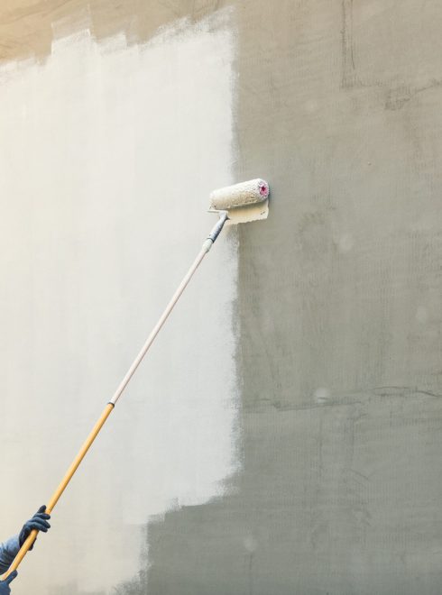 house painter painting building exterior with roller